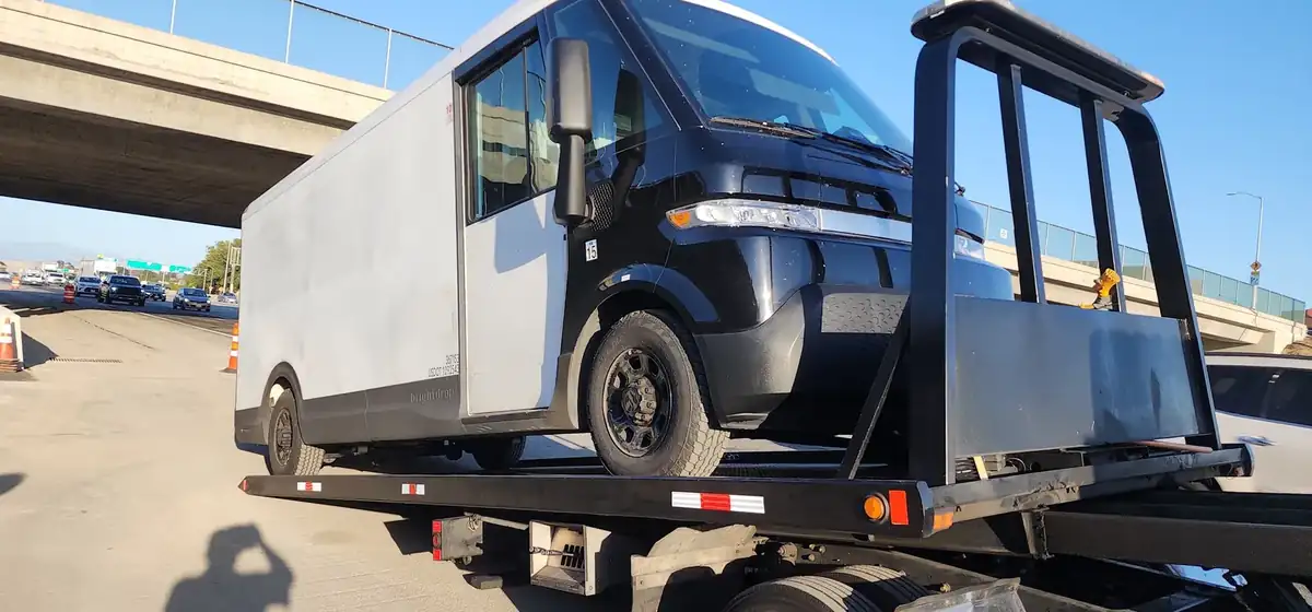 Geer's Towing flatbed hauling an electric delivery van on a Southern California freeway