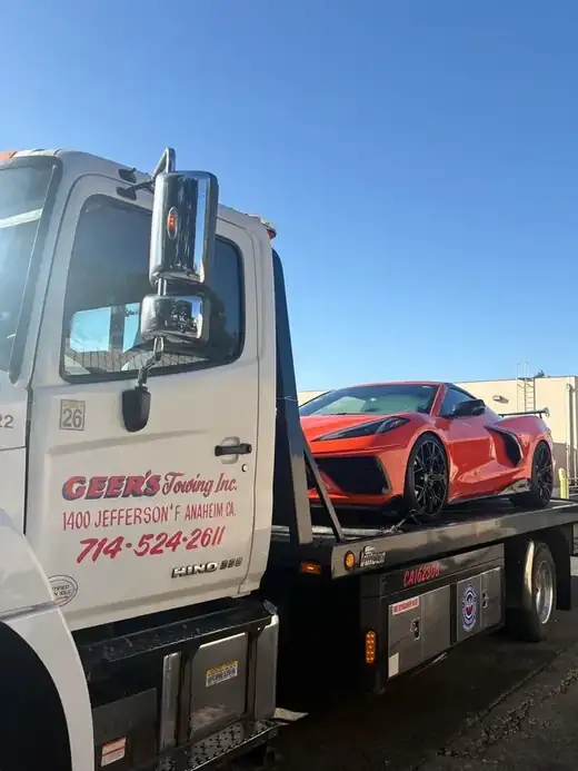 Geer's Towing flatbed transporting a red Chevrolet Corvette in Anaheim
