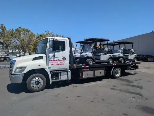 Geer's Towing flatbed transporting multiple golf carts for a commercial client