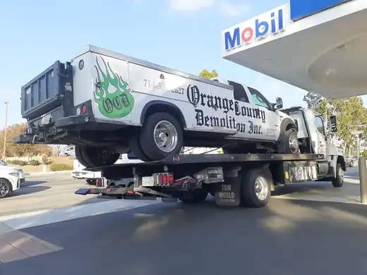 Geer's Towing flatbed transporting a commercial service truck in Orange County