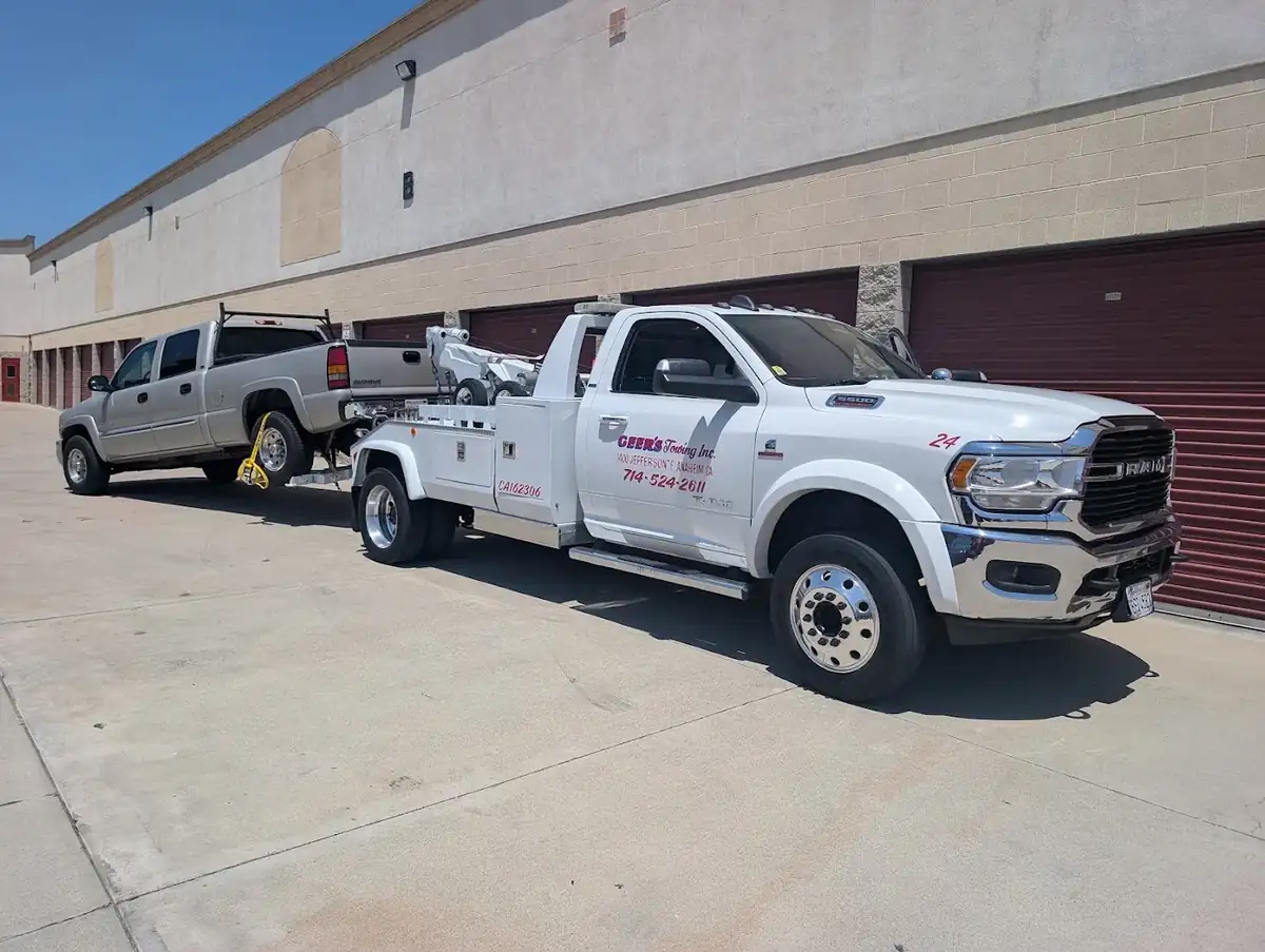 Geer's Towing Ram 5500 wheel-lift tow truck towing a GMC pickup truck